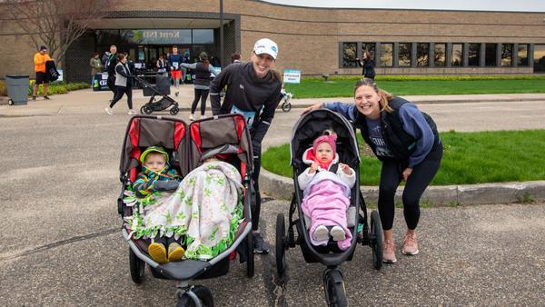 Two runners with kids in strollers at the race